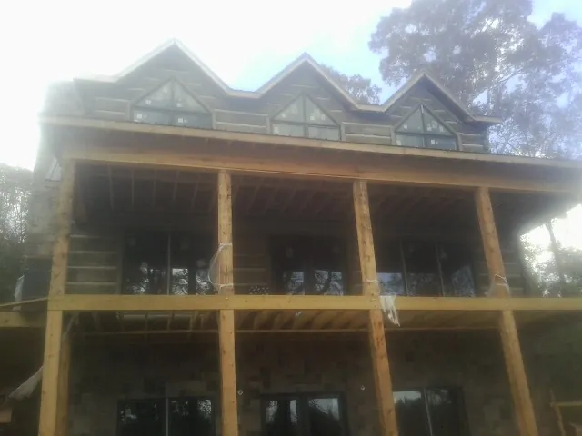 Dormers and porch framing on a large log home under construction — Roof Coating work by our crew in Cameron